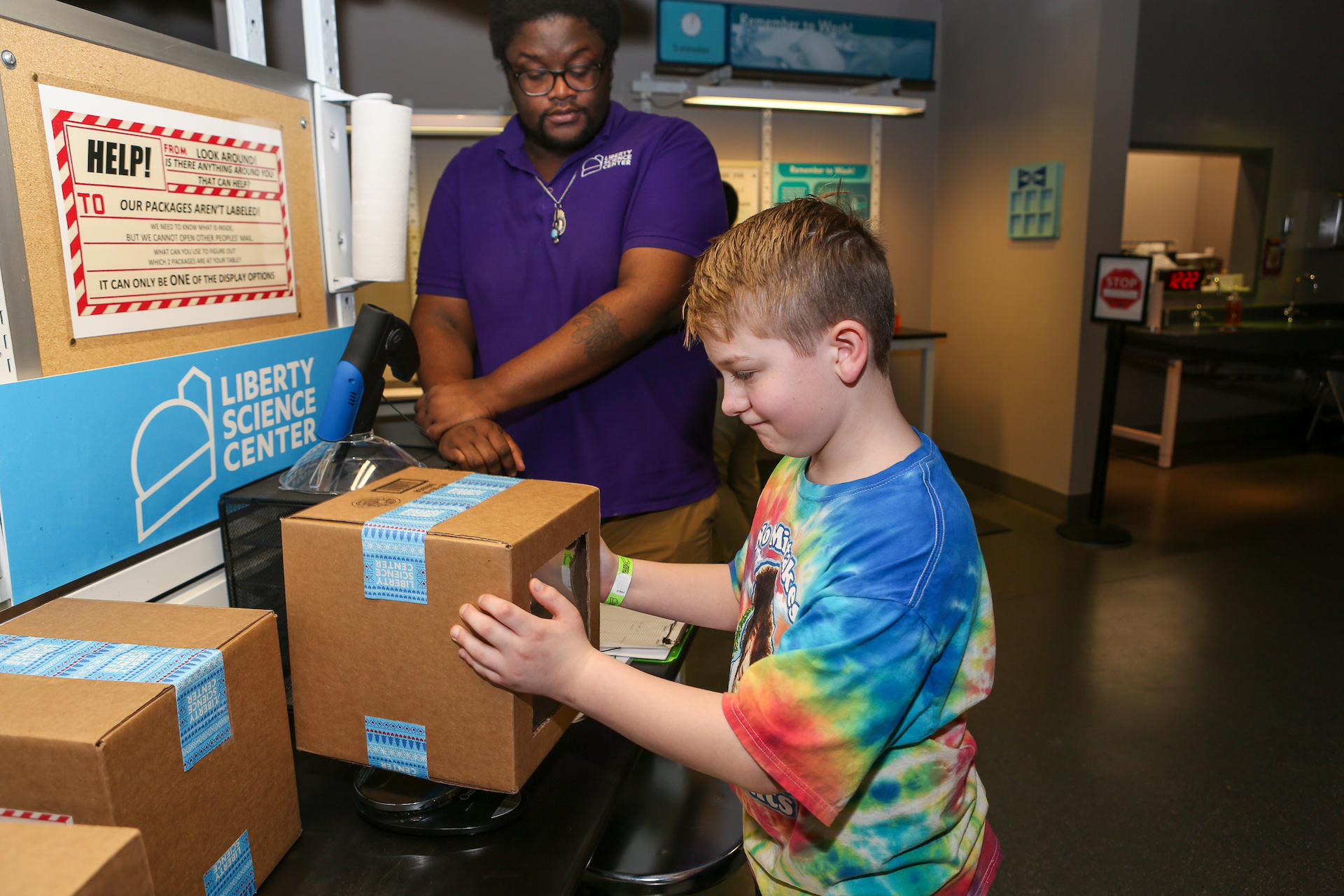 Kid investigating package at Puzzling Packages lab