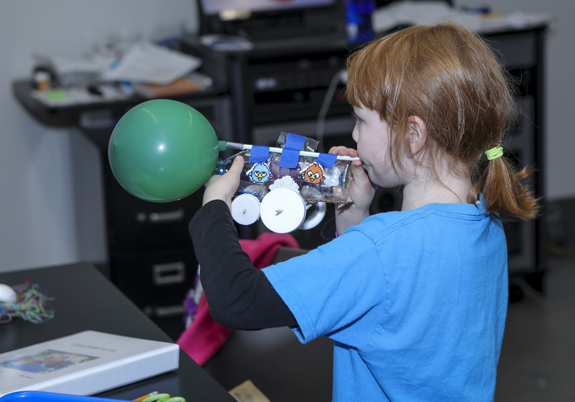 Girl blowing up balloon to use for Angry Birds transportation device
