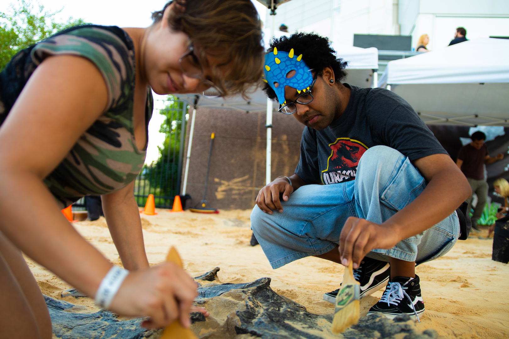 People using brushes to uncover fossils in Dino Dig exhibition