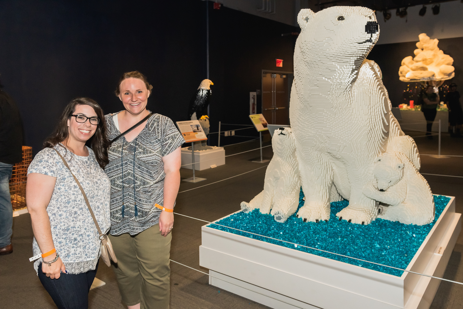 Girls enjoying the polar bear sculpture made out of LEGO pieces