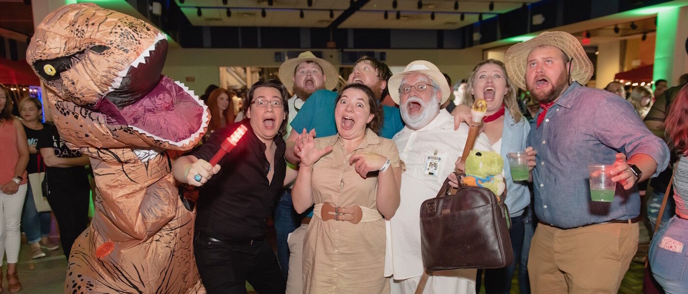 Guests playfully scream while posing with a dinosaur costume character